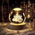 گوی شیشه‌ای لیزری طرح قصر آرزوها با نور زرد گرم و پایه چوبی